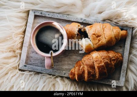 Tazza di caffè con croissant al cioccolato sul vassoio Foto Stock