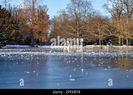 Karlsruhe, Germania - 12 febbraio 2021: Statua di una mano che tiene un telefono cellulare, a portata di mano, in uno stagno congelato nei giardini del Palazzo di Karlsruhe su una selce soleggiata Foto Stock