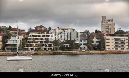 544 barca a vela ormeggiata al largo degli edifici sul lungomare della penisola di North Head visto dal traghetto Manly. Sydney-Australia. Foto Stock