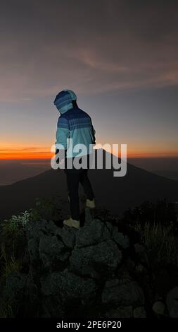 L'uomo saluta l'alba in montagna. Un uomo saluta l'alba. Giava Occidentale, Indonesia, 16 Marzo 2023 Foto Stock