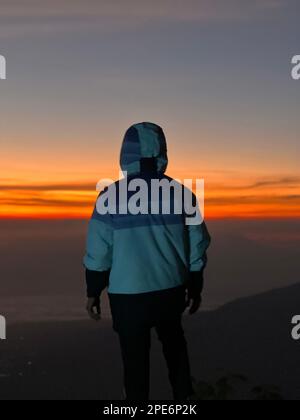 L'uomo saluta l'alba in montagna. Un uomo saluta l'alba. Giava Occidentale, Indonesia, 16 Marzo 2023 Foto Stock