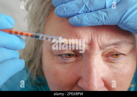 Donna anziana che ottiene l'iniezione di cura della pelle. Donna anziana che ha procedura di iniezione botox. Trattamento cosmetico con iniezione in clinica Foto Stock