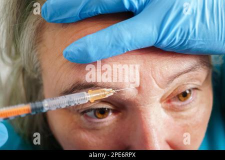 Donna anziana che ottiene l'iniezione di cura della pelle. Donna anziana che ha procedura di iniezione botox. Trattamento cosmetico con iniezione in clinica Foto Stock