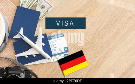 Bandiera della Germania con passaporto e aereo giocattolo su sfondo di legno. Concetto di viaggio in volo. Foto Stock