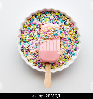 Una cakesicle fatta in casa in una ciotola di pastello spruzza. Ritaglio quadrato Foto Stock