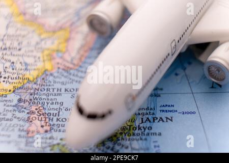 Primo piano dettaglio di un velivolo passeggeri in miniatura su una mappa colorata che si concentra su Tokyo Giappone attraverso la messa a fuoco selettiva, sfocatura dello sfondo Foto Stock