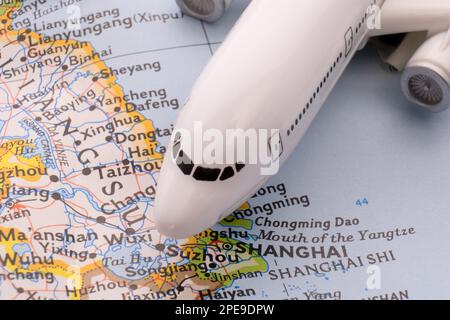 Primo piano dettaglio di un velivolo passeggeri in miniatura su una mappa colorata che si concentra su Shanghai, Cina attraverso la messa a fuoco selettiva, sfocatura dello sfondo Foto Stock