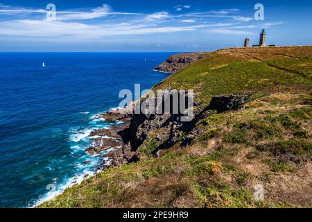 Scogliere sulla costa atlantica con l'antico faro a Cap Frehel in Bretagna, Francia; Phare du Cap Frehel Foto Stock