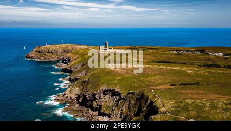 Scogliere sulla costa atlantica con l'antico faro a Cap Frehel in Bretagna, Francia; Phare du Cap Frehel Foto Stock