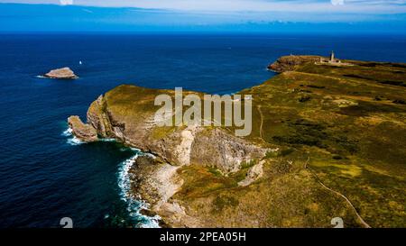 Scogliere sulla costa atlantica con l'antico faro a Cap Frehel in Bretagna, Francia; Phare du Cap Frehel Foto Stock