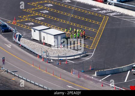 Persone al lavoro in piedi in una riunione di gruppo durante il giorno, porto di Lyttelton, Christchurch, Nuova Zelanda. Foto Stock