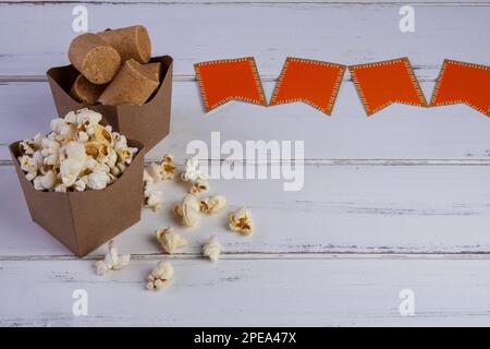 ciotole di popcorn e caramelle alle arachidi e bandiere di carta su un tavolo di legno bianco. Foto Stock