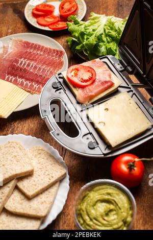 Macchina per sandwich. Cottura di panini con farciture diverse. Foto Stock