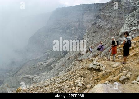 Turisti sulle pendici del cratere con vapore proveniente dalla bocca, Monte Ijen, Giava Orientale, Indonesia Foto Stock