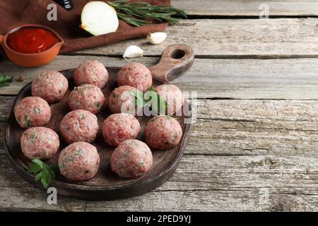 Molti polpette fresche crude e ingredienti su tavolo di legno, spazio per il testo Foto Stock