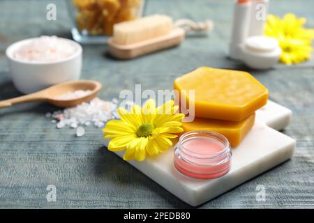 Balsamo, cera d'api naturale e fiore su tavola di legno blu Foto Stock