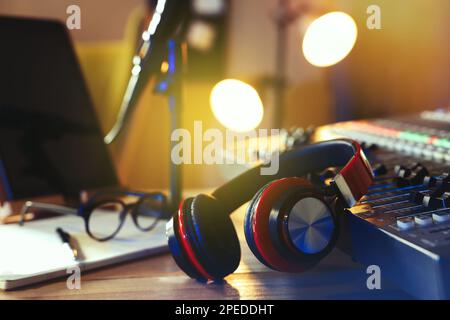 Cuffie vicino alla console di mixaggio professionale sul tavolo in studio radio Foto Stock