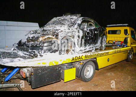 15 marzo 2023, Baden-Württemberg, Engelsbrand: Un'auto è coperta di schiuma dopo un incendio di un veicolo su un autocarro trainato dall'ADAC. Una macchina è bruciata su una strada di campagna vicino Engelsbrand (Enzkreis). La 22-year-old conducente femminile è stato in grado di salvarsi dalla macchina il Mercoledì sera e rimasto inferito, secondo la polizia. La donna aveva visto le fiamme salire dal vano motore. Ha fermato la macchina ad un incrocio e ha leggermente danneggiato un'altra macchina. Un utente della strada si è affrettato ad aiutare con un estintore. Ma né lui né i vigili del fuoco potrebbero impedire che l'auto si bruci completamente. Foto Stock