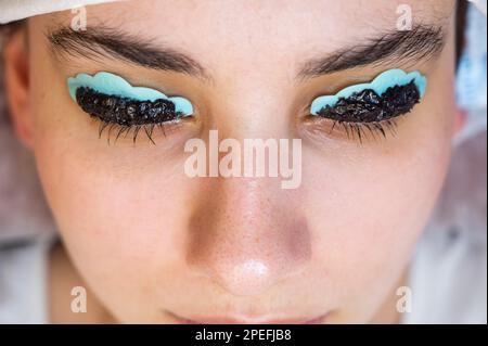 Primo piano ritratto di una donna sulla procedura di laminazione e tintura delle ciglia. Trucco permanente. Foto Stock