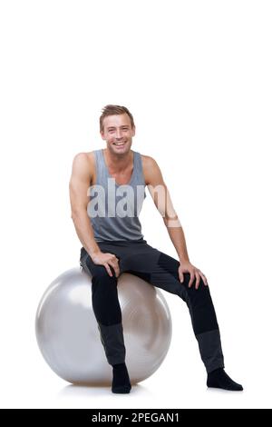 Sentirsi bene dopo un allenamento pesante. Ritratto di un uomo sorridente seduto su una palla da ginnastica. Foto Stock