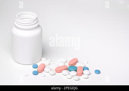 Spilled blu bianco pillole rosa da prescrizione aperta farmaco plastica bianca bottiglia sfondo grigio Foto Stock