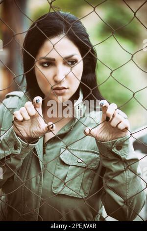 Donna seria che tiene recinto filo di pollo Foto Stock