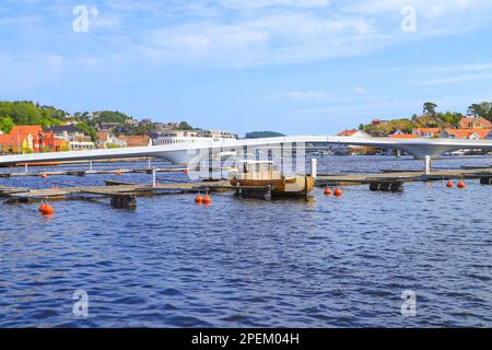 Una barca di legno nel porticciolo degli ospiti a Mandal con il ponte bianco, un ponte pedonale sullo sfondo, Norvegia Foto Stock