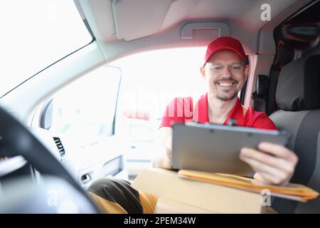 Il corriere è impegnato nella logistica della consegna e tiene in mano il tablet Foto Stock