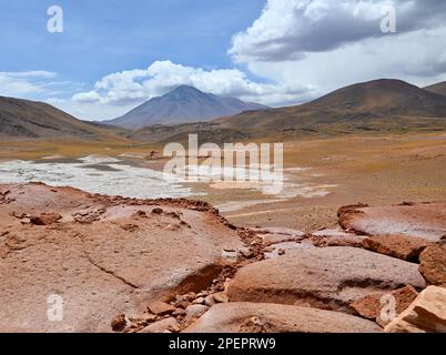 Un deserto con distese di sale circondato da grandi vulcani che dominano il paesaggio Foto Stock