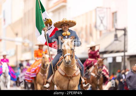 Brownsville, Texas, USA - 26 febbraio 2022: Charro Days Grand International Parade, Man in charro vestito portava la bandiera messicana mentre cavalcava un hors Foto Stock