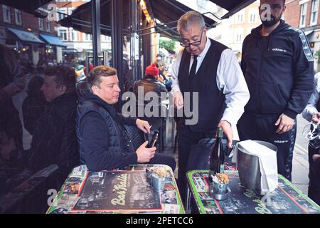 Thomas Henry Skinner, l'uomo d'affari inglese e la personalità televisiva guarda il cameriere versare vino bianco a Soho, Londra, 02 2023 Foto Stock