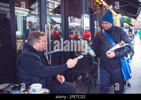 Thomas Henry Skinner l'uomo d'affari inglese e la personalità televisiva danno soldi ad un uomo senza casa, a Soho, Londra 16 02 2023 Foto Stock