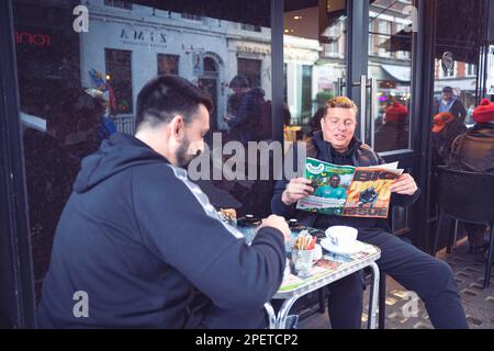 Thomas Henry Skinner l'uomo d'affari inglese e la personalità televisiva che legge Big Issue con un amico a Soho, nuvoloso inverno Londra, 2023 Foto Stock