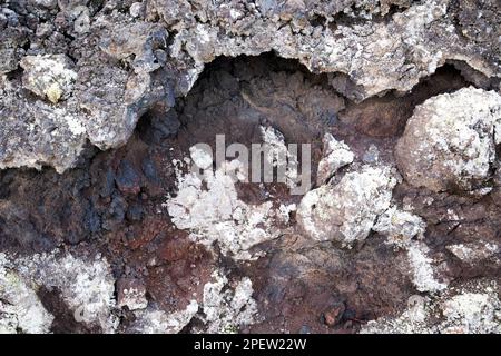 Rocce rosse e nere nella parte di raffreddamento del gap di ventilazione coperta in lichene nella sezione trasversale del flusso lavico parque nacional de timanfaya Lanzarote, Isole Canarie, SPAI Foto Stock