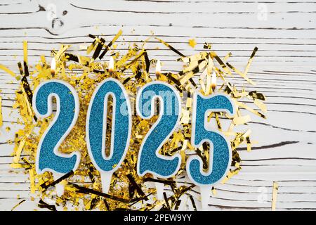 Sfondo festivo Felice anno nuovo 2025. Numeri dell'anno 2025 realizzati da candele blu su festoso sfondo di legno bianco. Festeggiamo le vacanze di Capodanno Foto Stock