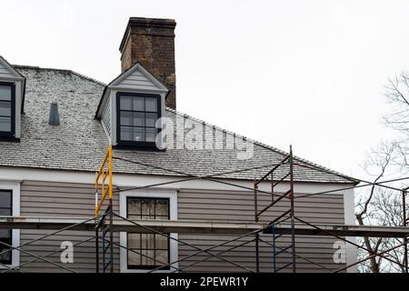 Finestre e dormitori vintage a doppia appesa su un tetto esterno in cedro di color beige di un vecchio edificio. Le vecchie finestre sono nere e bianche. Foto Stock