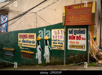 Annunci colorati dipinti per le aziende locali su un muro in una strada laterale a Dalat, Vietnam. Foto Stock