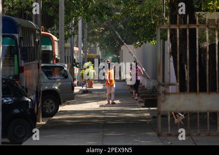 Yangon, Myanmar - 19 dicembre 2019: Un uomo si gira per stare coraggioso ad una donna che fa jogging sul Merchant Rd, Yangon, Birmania, Myanmar Foto Stock