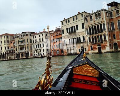 Una tradizionale gondola veneziana che scivola lungo un pittoresco canale nella storica città di Venezia Foto Stock