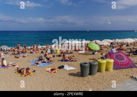 Barcellona, Spagna Barceloneta Beach nuotatori prendere il sole sotto un sole luminoso in una giornata d'estate. Foto Stock