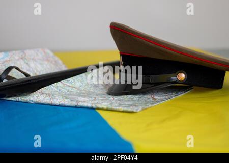 Bandiera Ucraina con diversi oggetti militari come un fucile, un cappello militare russo, una mappa o una difesa di polizia Foto Stock