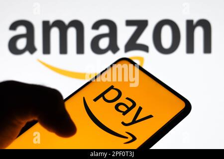 In questa immagine il logo Amazon Pay visualizzato sullo smartphone e sullo sfondo il logo Amazon. Foto Stock