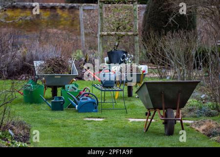 scena di lavoro attrezzatura da giardinaggio carriole e lattine di irrigazione in giardino in uso per prepararsi per la primavera Foto Stock