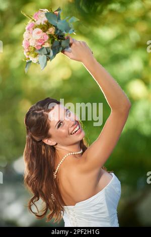 Whos il prossimo per ottenere hitched. Foto retrospettiva di una giovane sposa felice in procinto di lanciare il suo bouquet sulla spalla. Foto Stock
