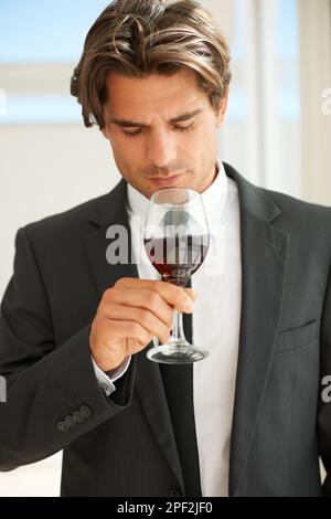 Controllare il naso del vino. Un bel conoscitore di vino che si gode un bicchiere di vino rosso. Foto Stock