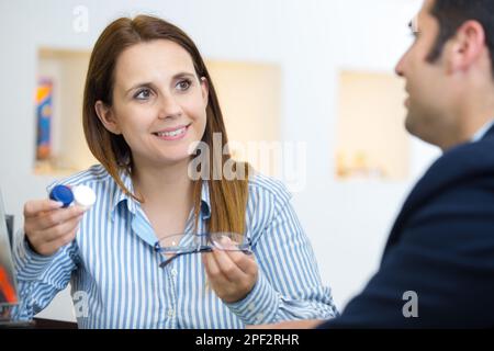 donna che sceglie tra lenti a contatto o occhiali Foto Stock