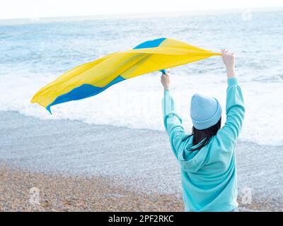 Donna brunnete con cappuccio blu e cappello blu con bandiera nazionale dell'Ucraina, concetto patriottico Foto Stock