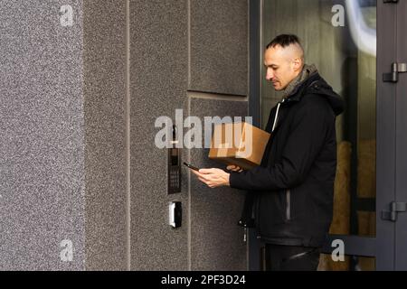 L'uomo utilizza smartphone per aprire la porta della sua casa Foto Stock