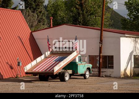 Un camion a pianale decorato con tre bandiere americane, una grande bandiera che giace nel letto, Chama, New Mexico, USA. Foto Stock