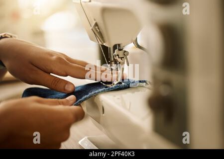 Zoom nelle mani di un cucito seamstress cucire un pezzo di tessuto. Stilista di moda cucendo un pezzo di tessuto.Closeup di designer sartoria tessuto denim in Foto Stock